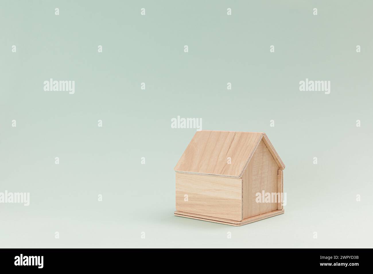 Semplice modello di casa in legno isolato su sfondo verde pallido Foto Stock