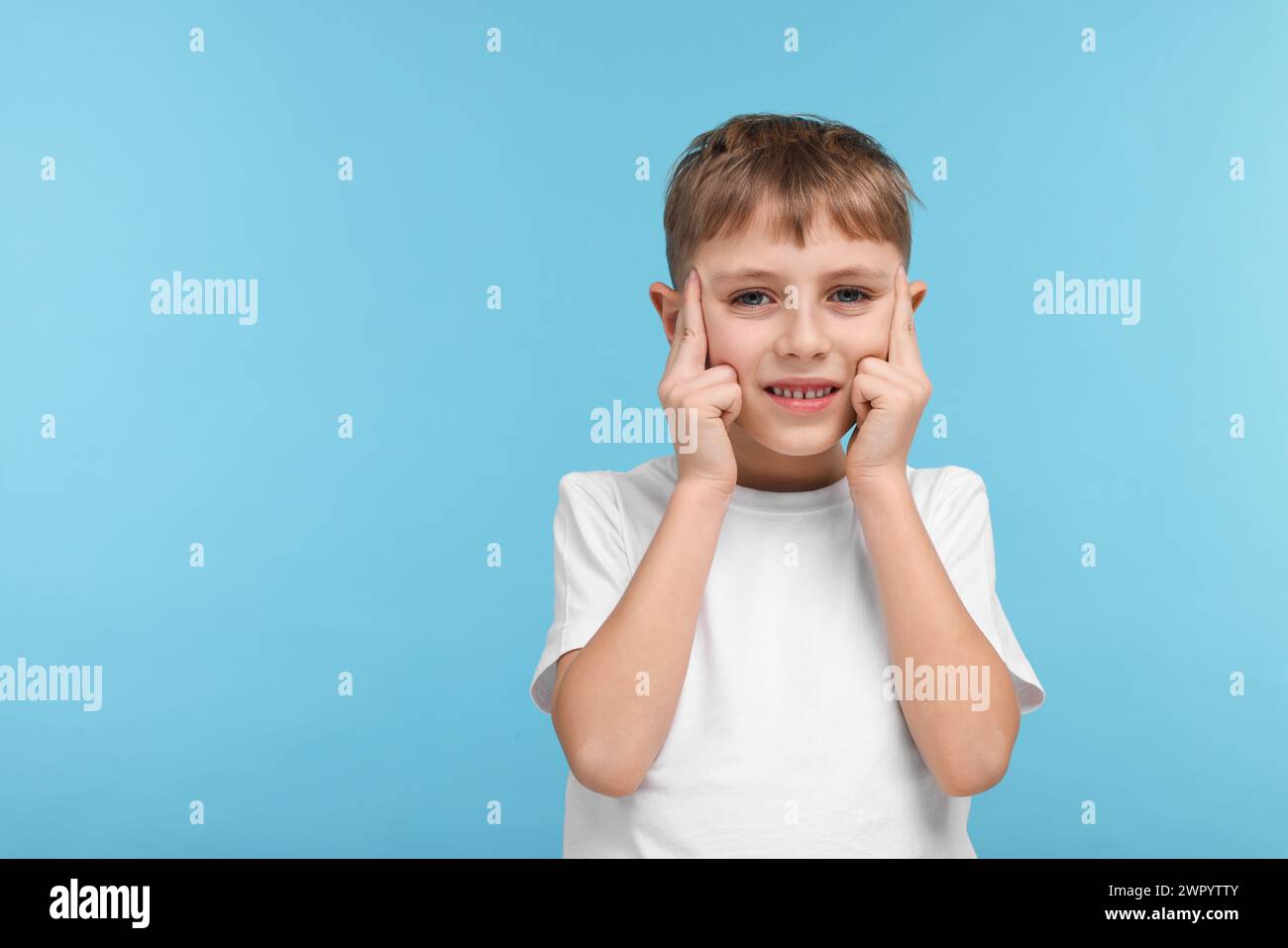 Bambino che soffre di mal di testa su sfondo azzurro, spazio per il testo Foto Stock
