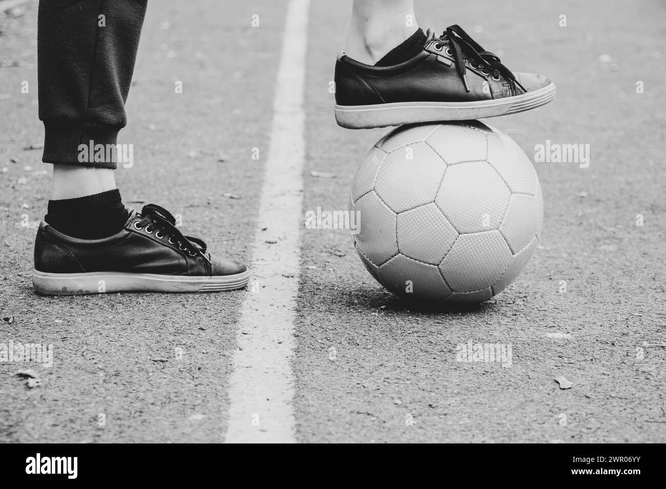 Gambe femminili su un campo di calcio e una palla di calcio grigia in Ucraina, giocando a calcio in cortile, sport Foto Stock