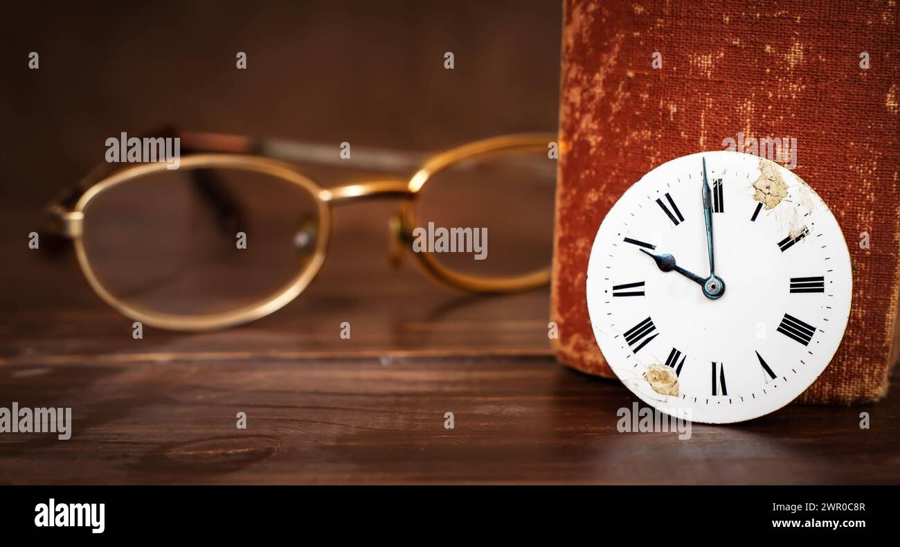 Occhiali da vista con un vecchio libro e un orologio. Narrazione, storia. Foto Stock