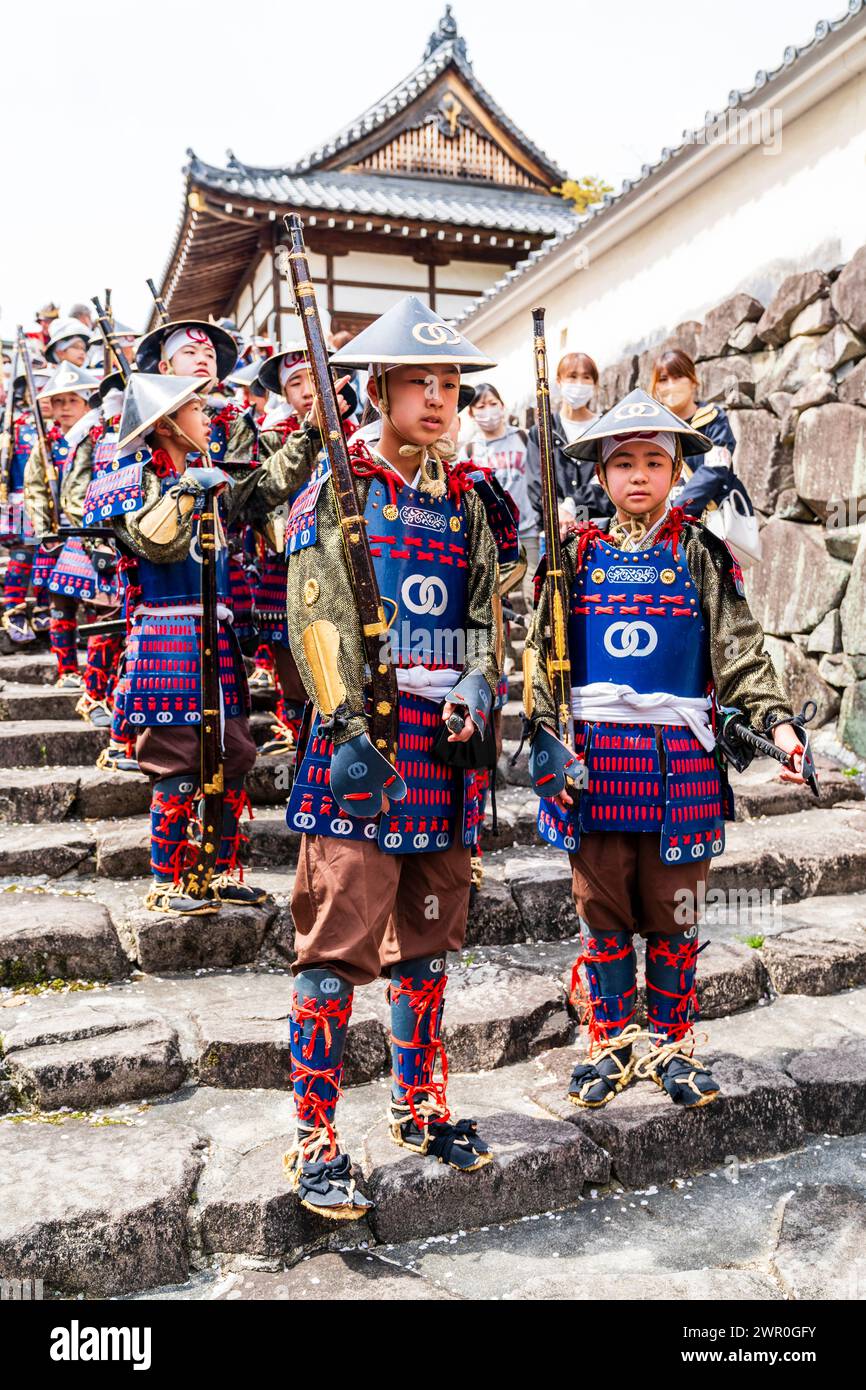 Bambini giapponesi vestiti da soldati ashigaru Teppou con pistole a fiammifero in piedi su gradini di pietra al castello di Tatsuno durante la parata dei samurai. Foto Stock