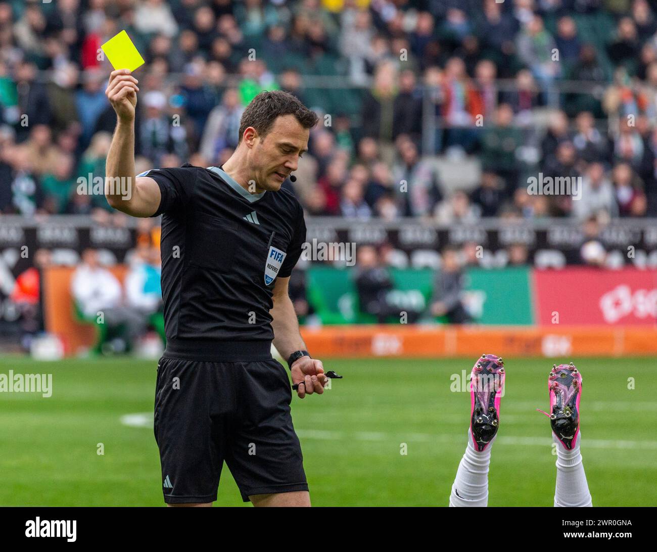 Sport, calcio, Bundesliga, 2023/2024, Borussia Moenchengladbach vs. 1. FC Koeln 3-3, Stadium Borussia Park, umorismo, scena divertente, l'arbitro Felix Zwayer presenta il cartellino giallo, visibile lungo il fondo ci sono solo due gambe di calcio, LE NORMATIVE DFL VIETANO QUALSIASI USO DI FOTOGRAFIE COME SEQUENZE DI IMMAGINI E/O QUASI-VIDEO Foto Stock
