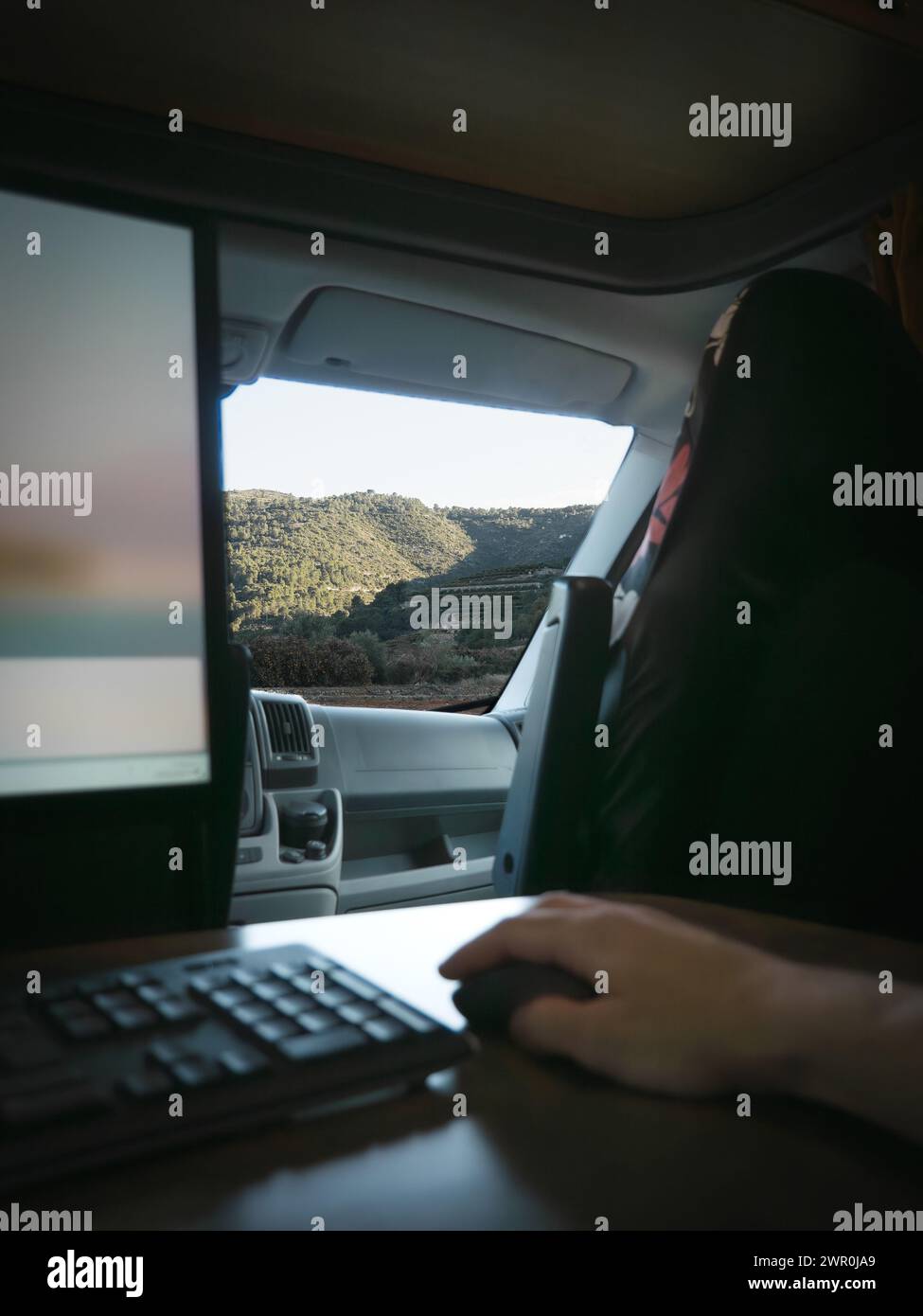 Persona non riconoscibile nomade digitale che lavora online con il computer all'interno del camper per mentre si gode la vista sulla natura Foto Stock
