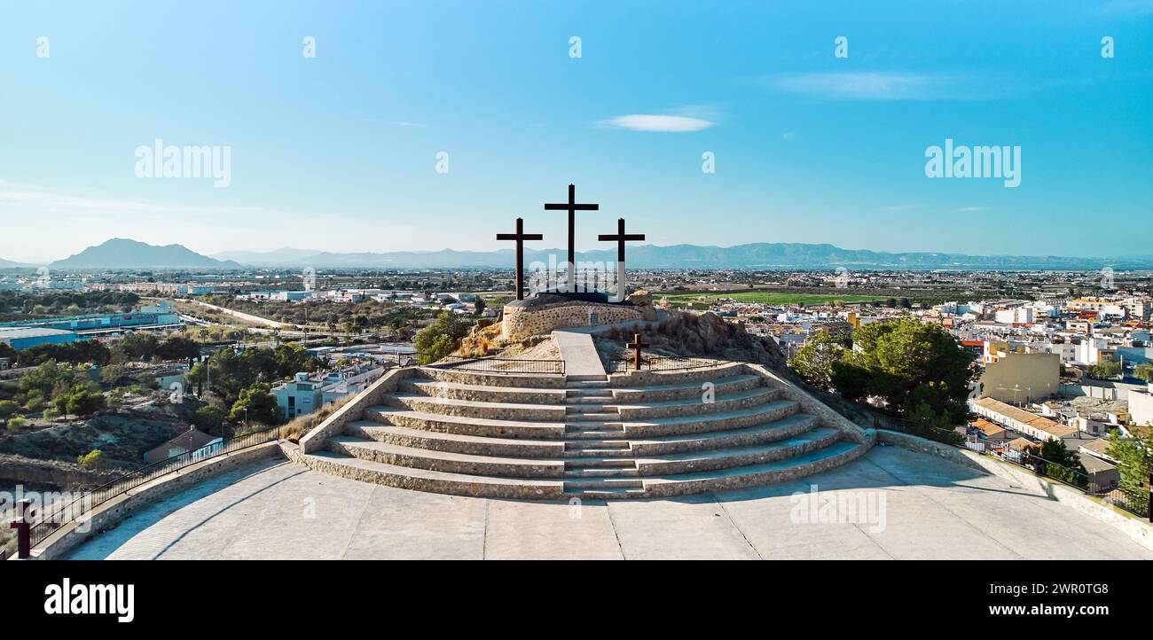 Vista aerea del paesaggio cittadino di Rojales con Monte Calvario e tre croci contro il cielo blu. Rojales, città, Spagna Foto Stock