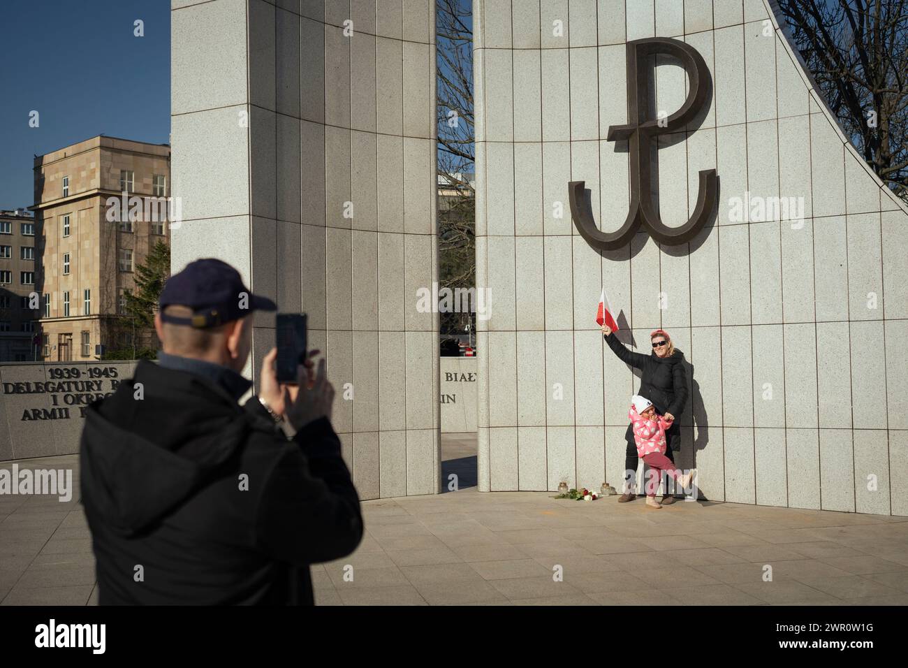 Una donna e un bambino si fanno fotografare sotto un segno dell'esercito della resistenza polacca (Kotwica) vicino al parlamento (Sejm) dopo una manifestazione contro la guerra del 09 Foto Stock