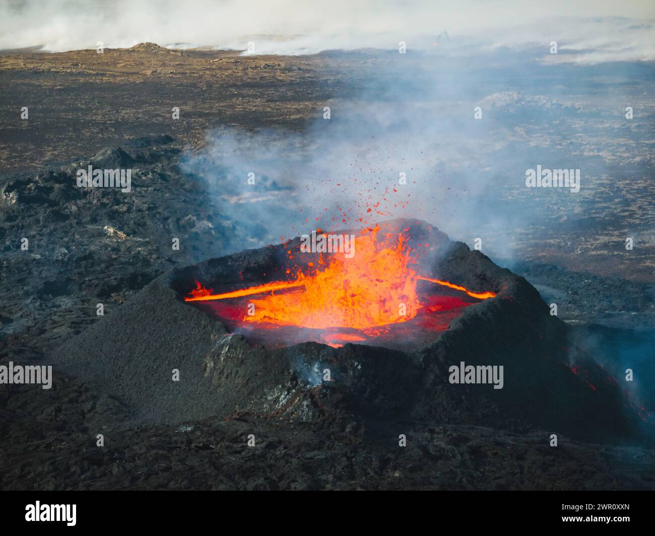 Eruzione vulcanica in Islanda, cratere sommitale, espulsione di gas e lava fusa che fuoriesce da un punto di ventilazione, vista aerea laterale. Pericolo naturale e geotermico Foto Stock