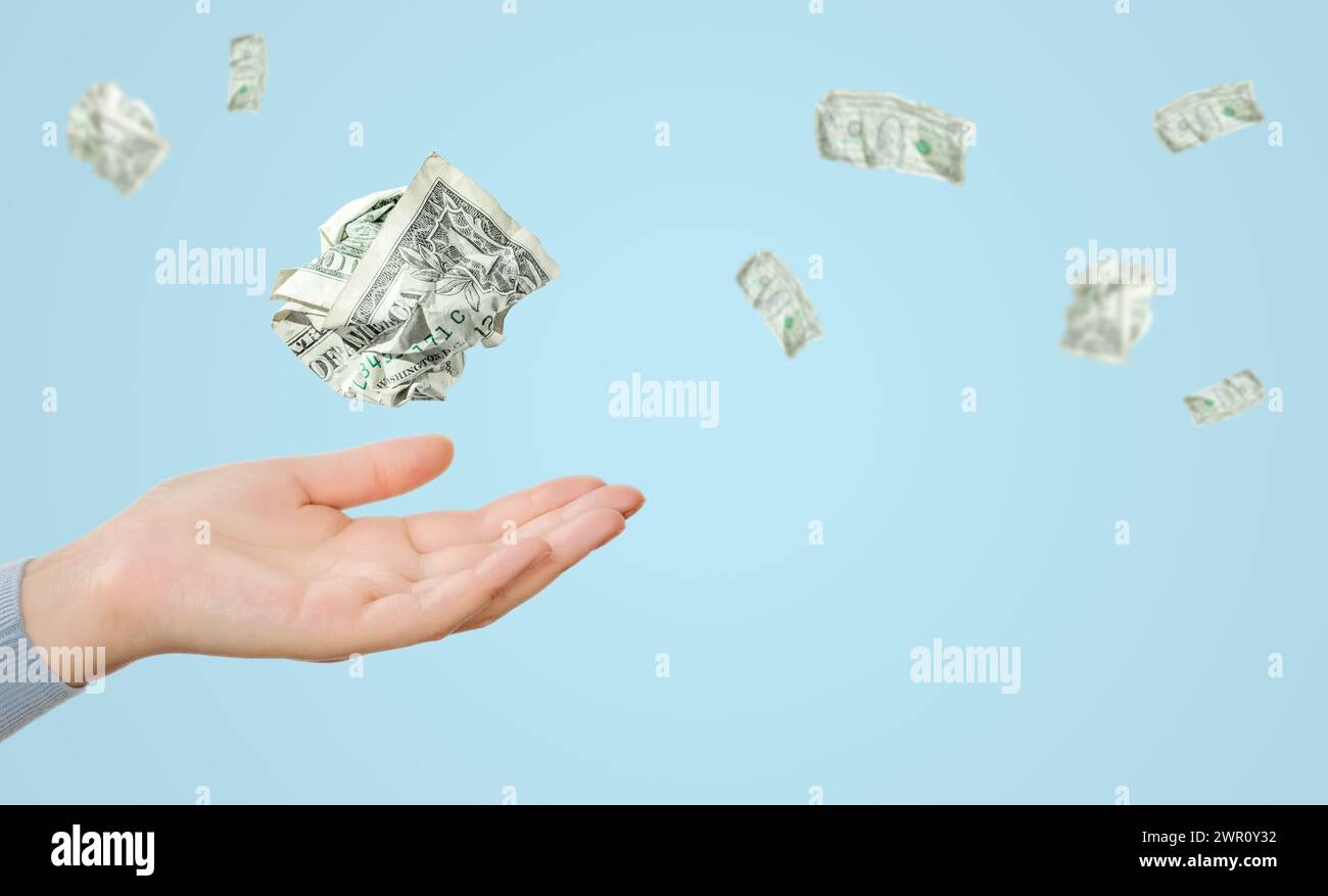 Le banconote da un dollaro volavano sopra la mano femminile su sfondo blu Foto Stock