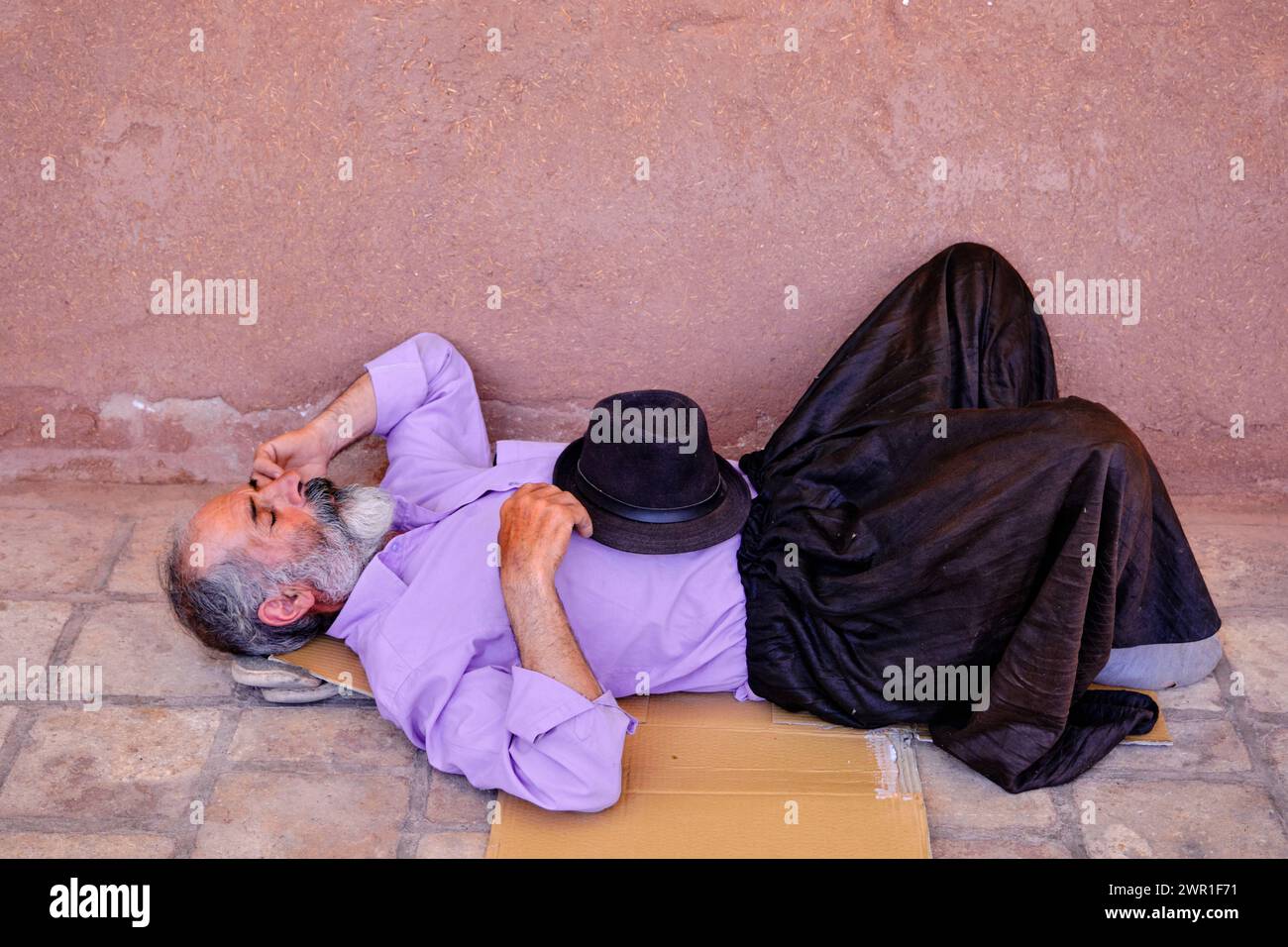 Abyenah , Iran, 07.01.2023: Un vecchio che dorme fuori terra, abiti da tradizione per anziani. Foto Stock