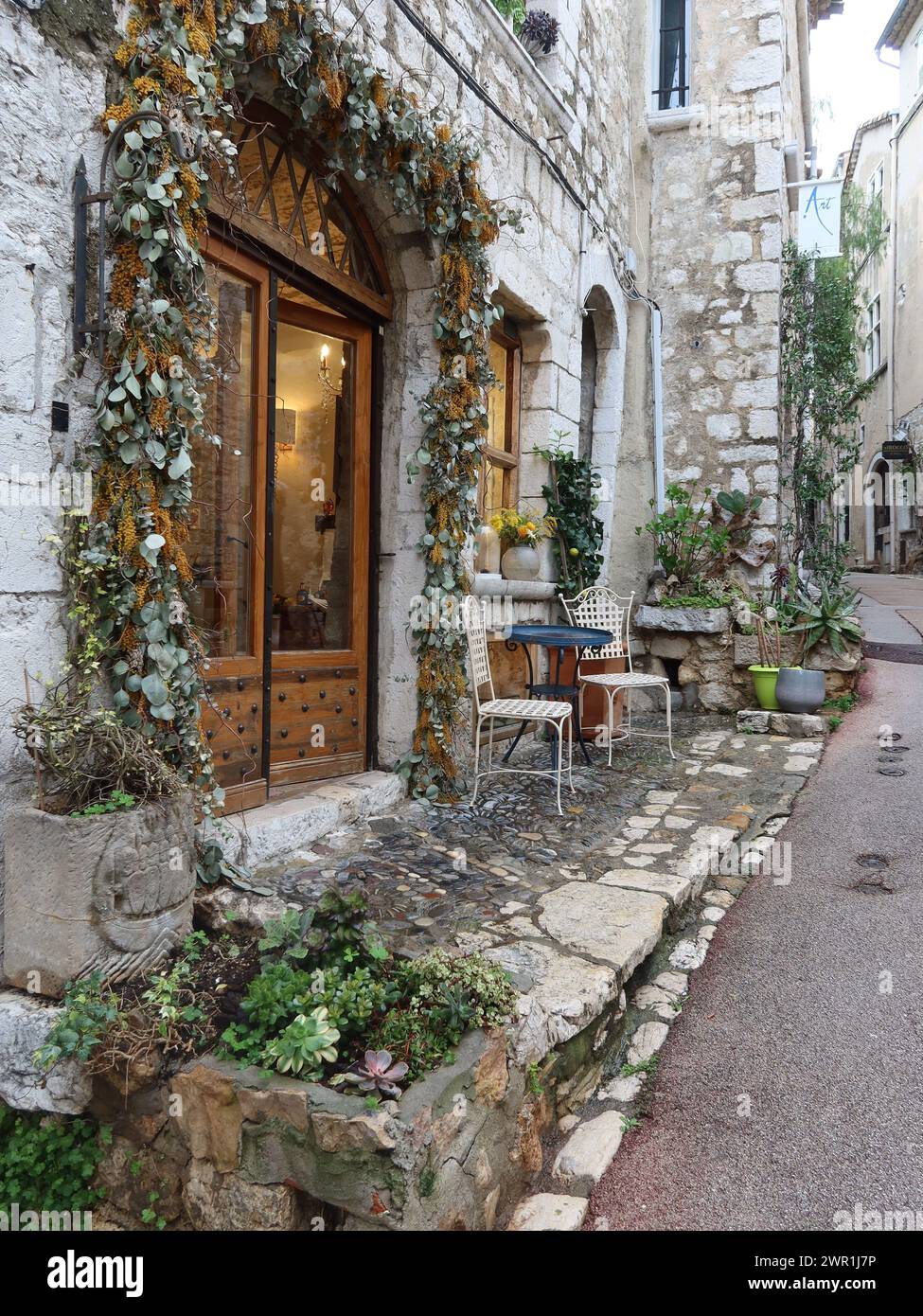 Architettura collinare della Riviera francese: Vista di un pittoresco edificio storico e di una strada acciottolata nel borgo medievale di Saint-Paul de Vence. Foto Stock