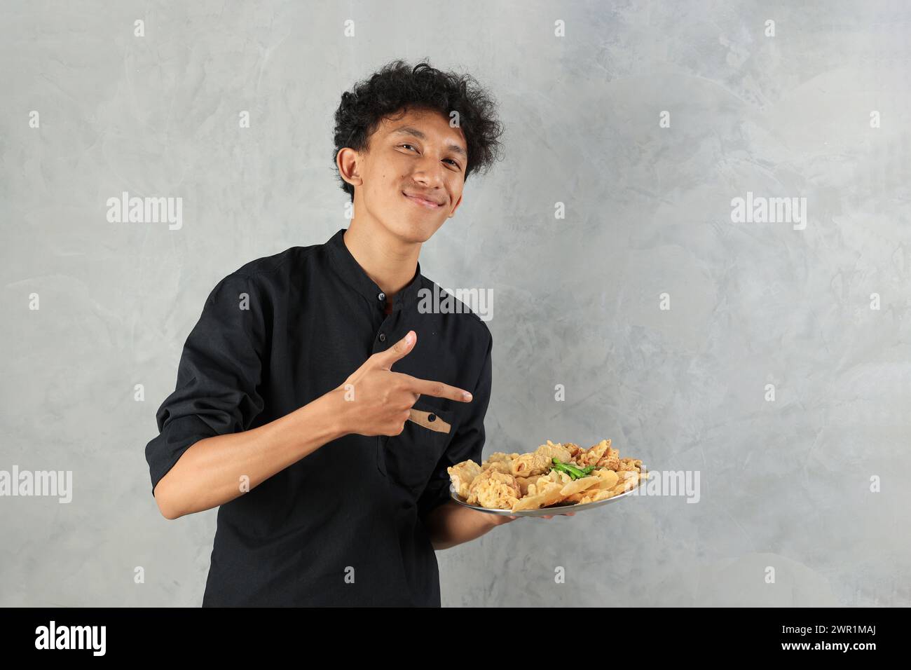 Felice uomo asiatico che tiene vari Gorengan con Green Chilli per rompere il veloce Buka Puasa Foto Stock