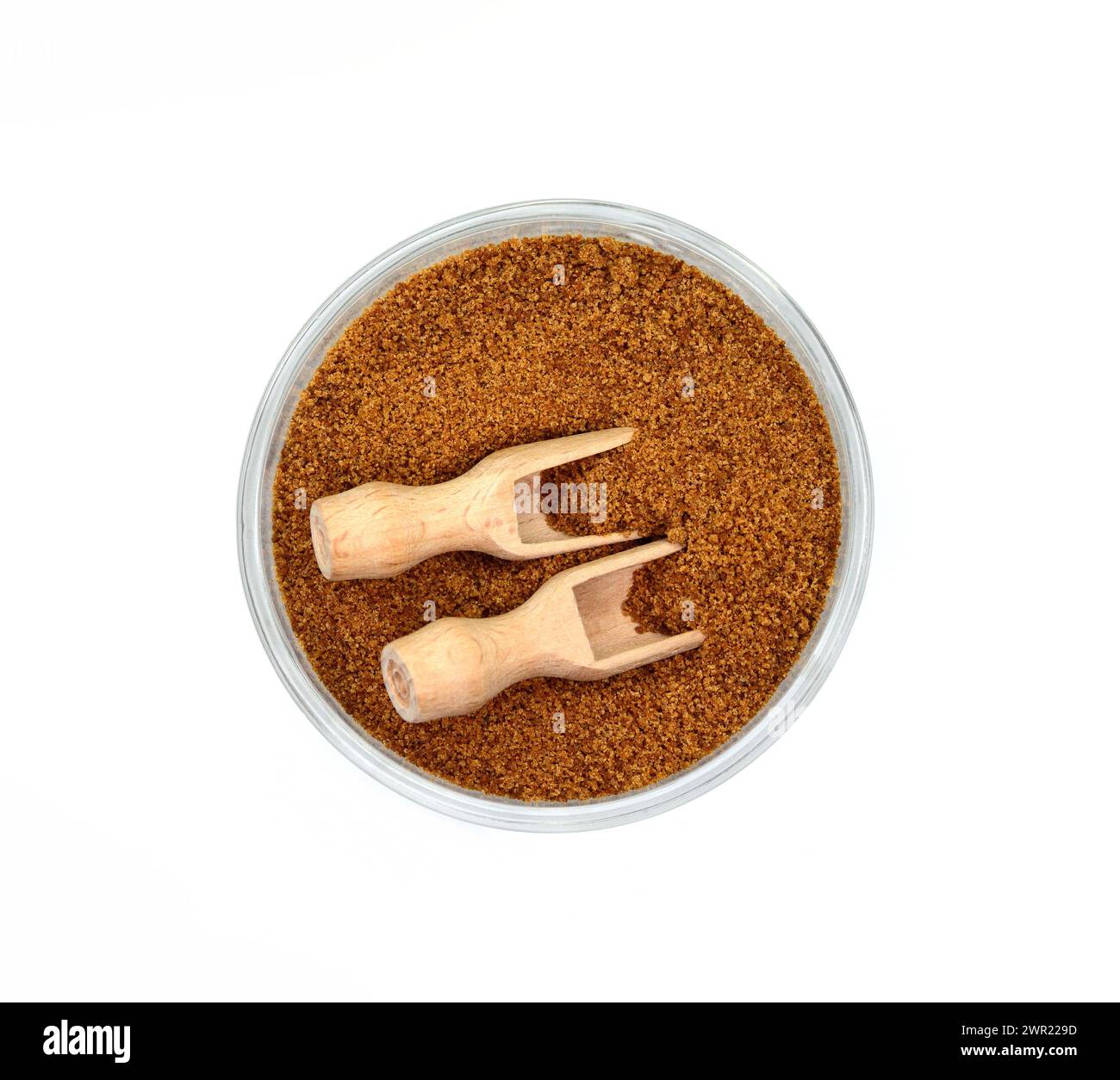 Zucchero di palma di cocco in un recipiente con paletta di legno isolata su bianco. zucchero di palma da cocco marrone. Foto Stock