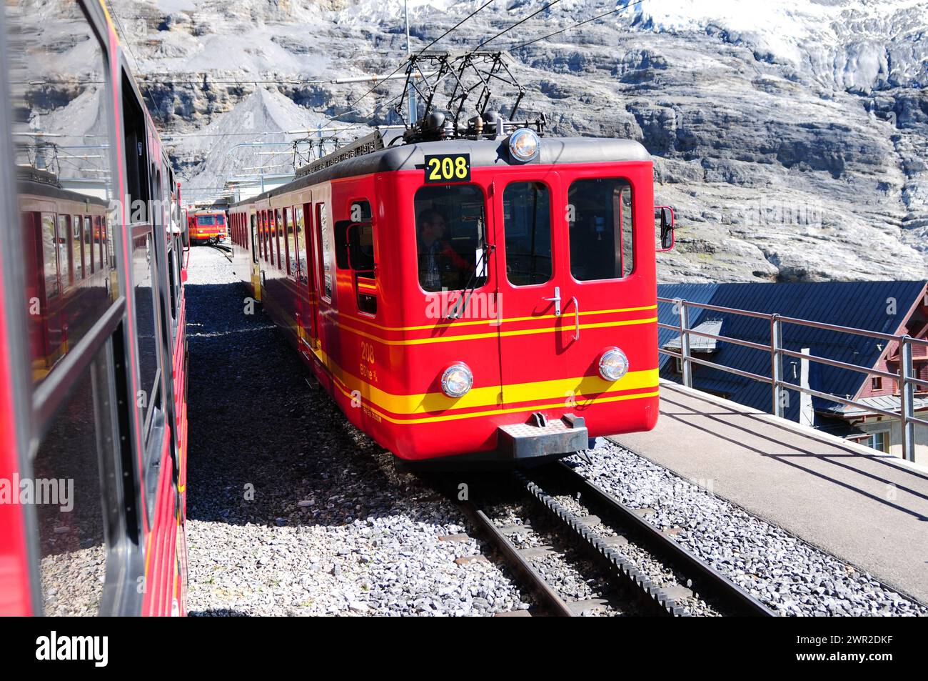 Treni Jungfraujoch che si attraversano ai piedi del ghiacciaio Mönchs nelle alpi svizzere | Die Jungfraujoch-Bahnen kreuzen sich am Fusse des Mönch Foto Stock