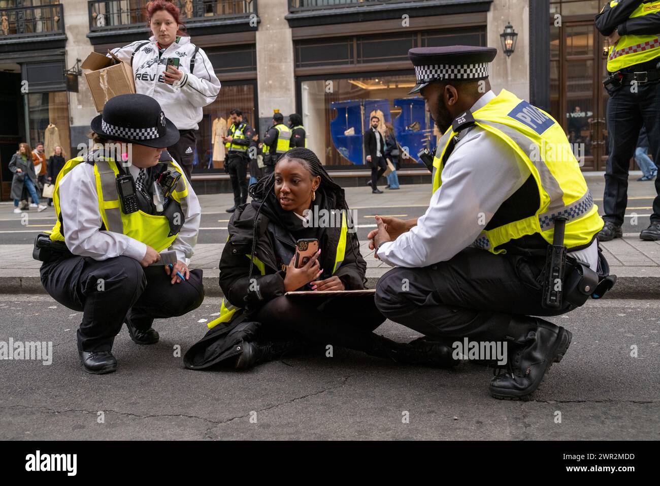 Gli agenti della polizia metropolitana incoraggiano un manifestante congolese a smettere di bloccare la strada durante la protesta. Protesta congolese britannica contro lo sfruttamento minerario e l'abuso di donne da parte dell'esercito ruandese nella Repubblica democratica del Congo. I manifestanti marciano dal quartier generale della BBC London a Portland Place lungo Regent Street fino a Trafalgar Square. I negozi di apparecchiature per telefoni cellulari e computer sono considerati il più grande consumatore di minerali di valore contestato. (Foto di James Willoughby/SOPA Images/Sipa USA) Foto Stock