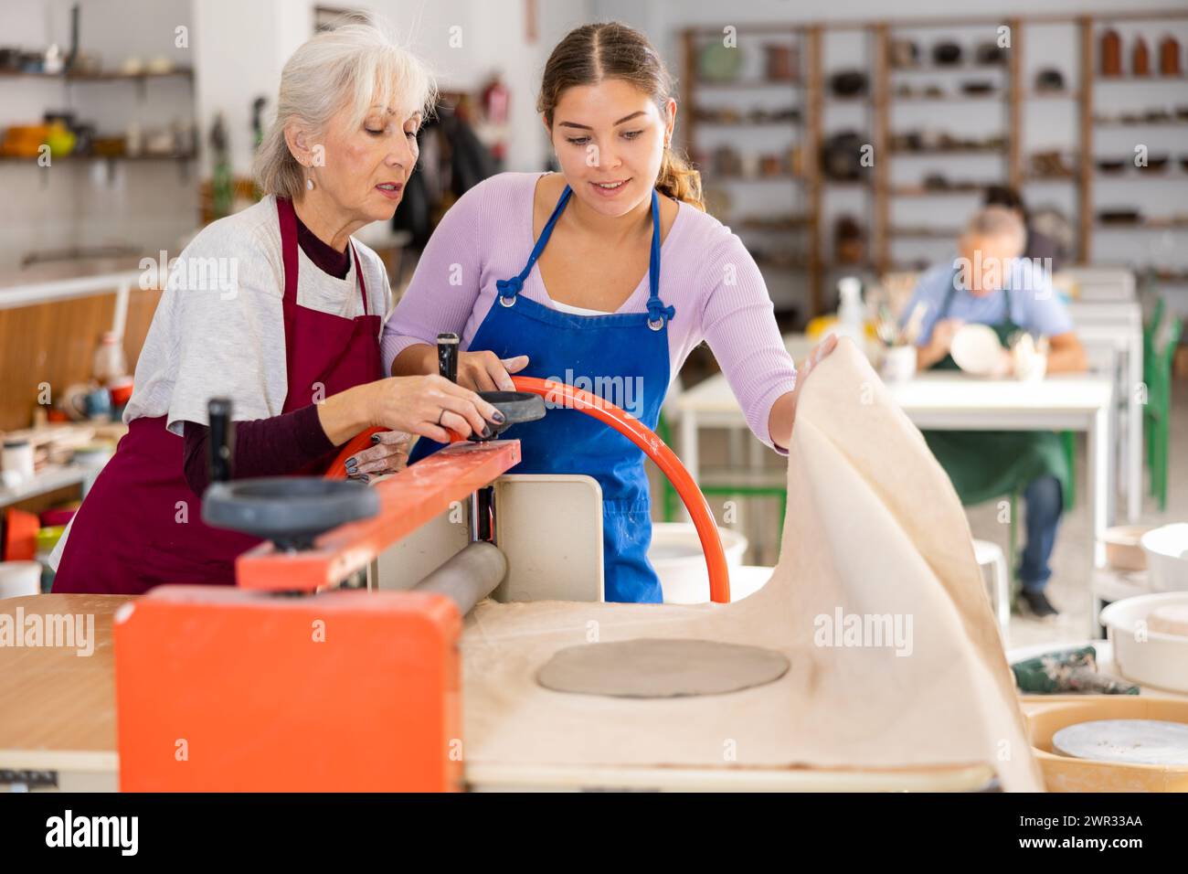 le donne in officina ceramica lavorano con la pressa a rulli Foto Stock