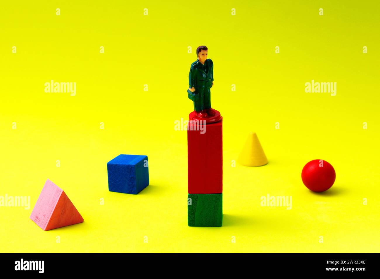 Executive al livello più alto circondato da figure geometriche di colori diversi Foto Stock