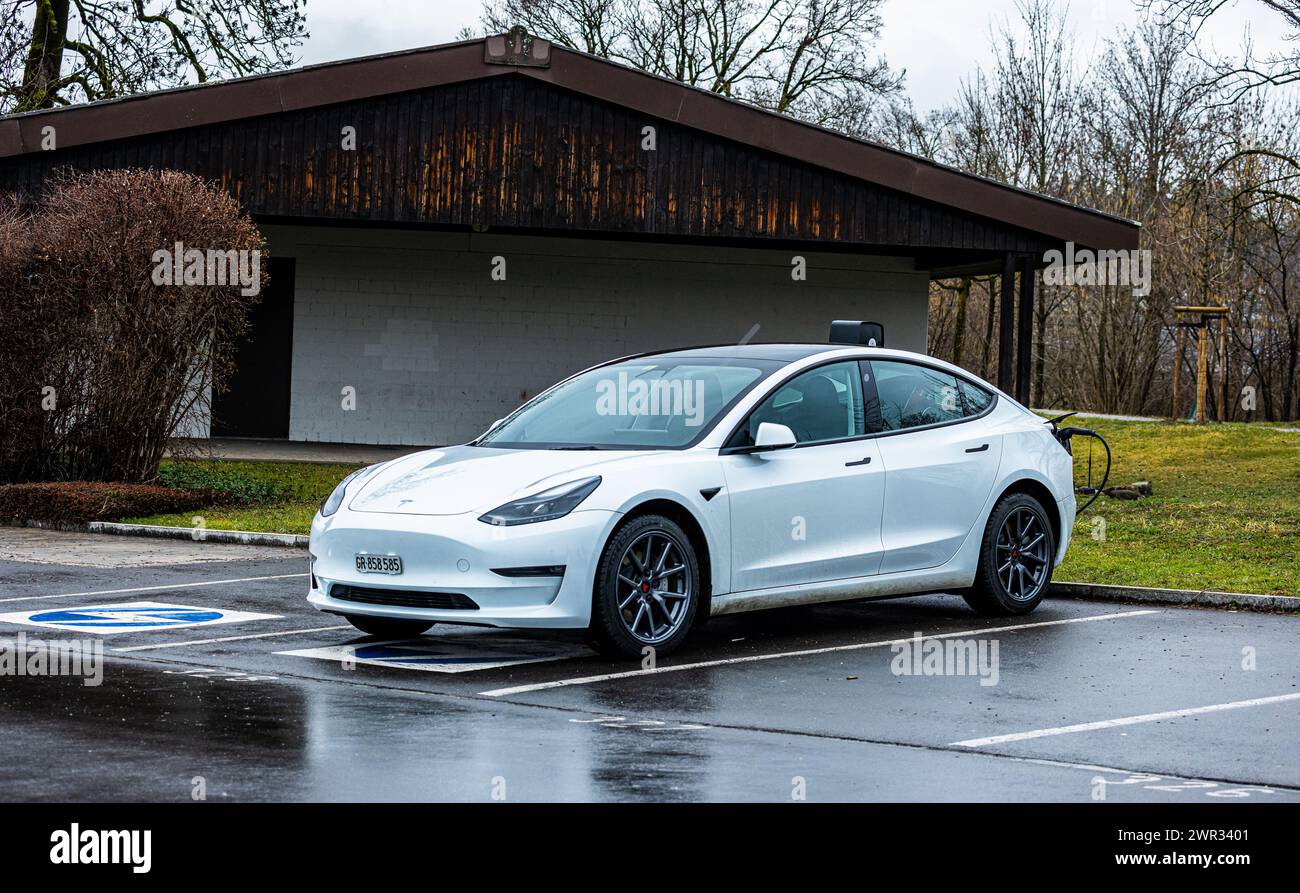 Ein Tesla Model 3 wird bei regnerisch, nassem Wetter an einer Ladestation aufgeladen. (Rapperswil-Jona, Svizzera, 25.02.2023) Foto Stock