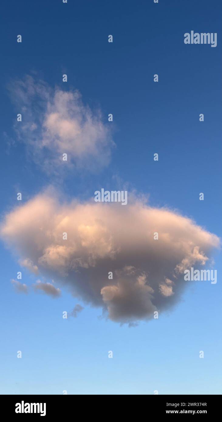 Nuvola di cumulus grigia solitaria al tramonto con cielo blu Foto Stock