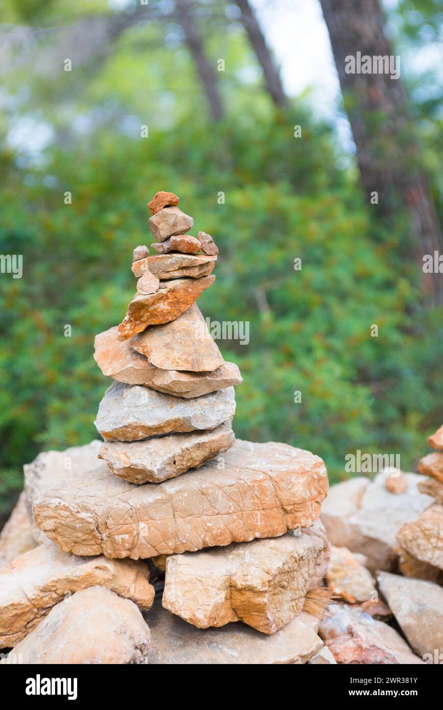 Le pietre leggermente rosse, piene di attenzione, formano una figura in pietra, un cairn, un waymark, un marcatore nel bosco, un sentiero escursionistico da Sant Elm alla vecchia torre di guardia Foto Stock