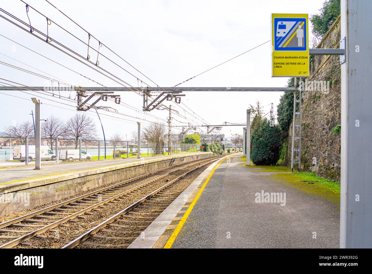piattaforma ferroviaria con linea gialla in modo che i passeggeri non passino a rischio di caduta sulla linea. Cartello segnaletico per non attraversare la linea gialla.Portu Foto Stock