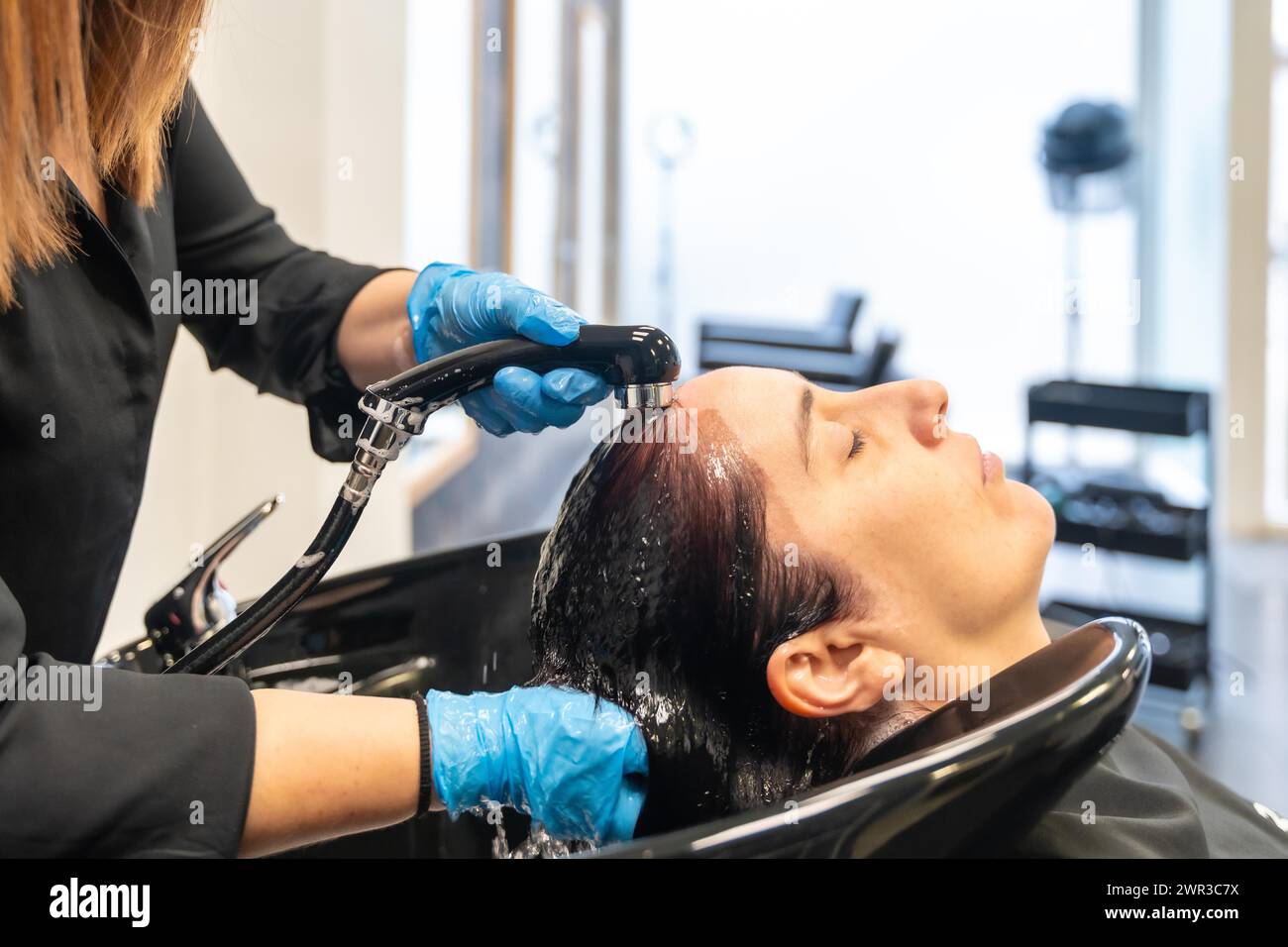 Donna rilassata con gli occhi chiusi che si lava i capelli in un salone di bellezza Foto Stock