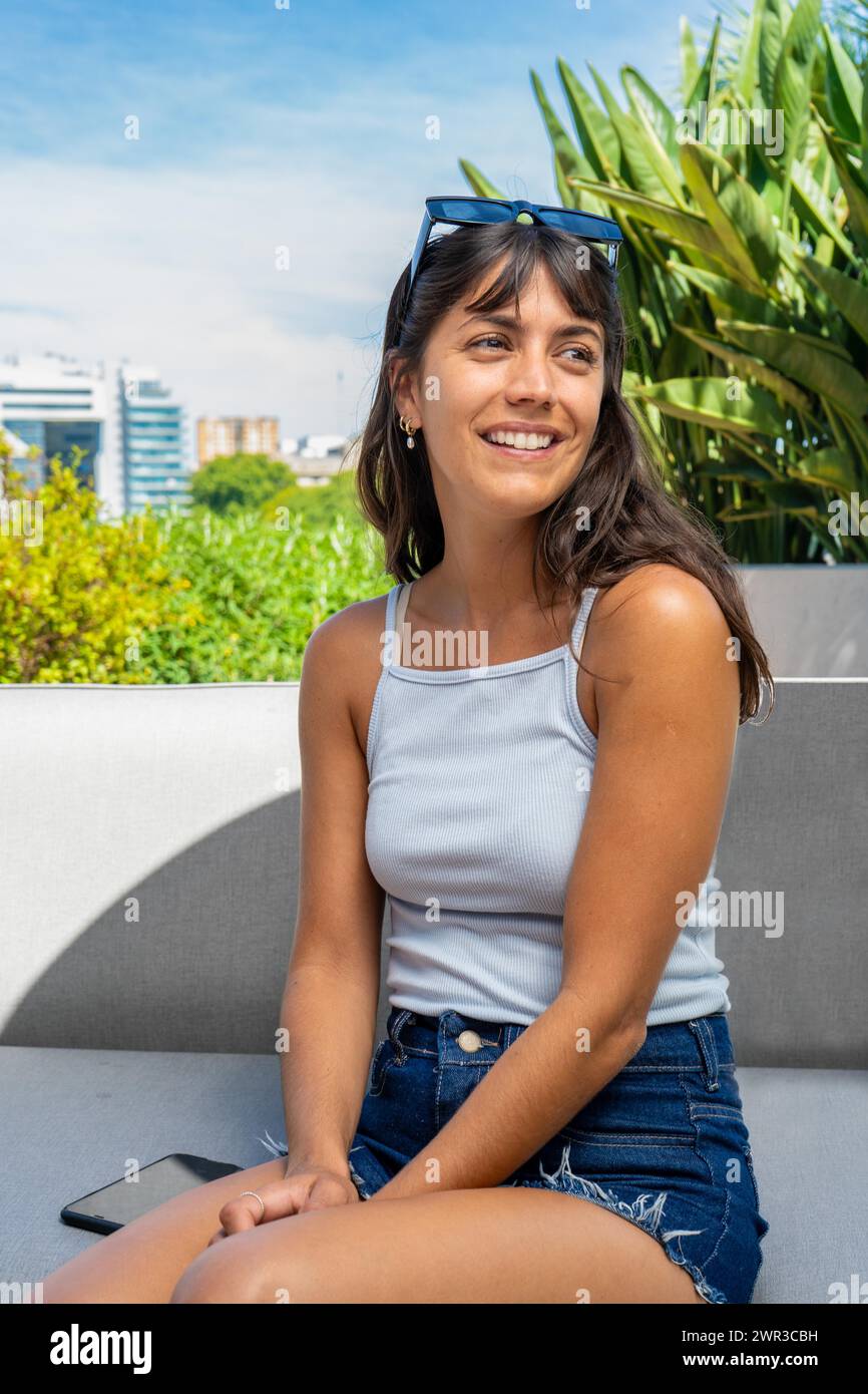 Ritratto di una donna seduta su un divano con le braccia unite scatto verticale Foto Stock