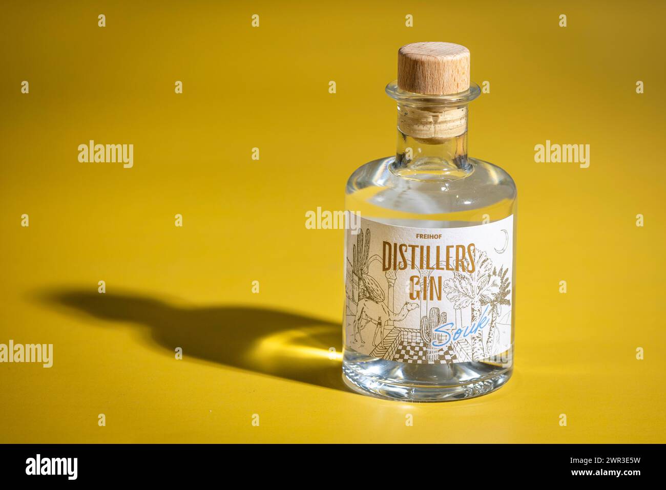 Bottiglia di gin su sfondo giallo con ombre interessanti Foto Stock