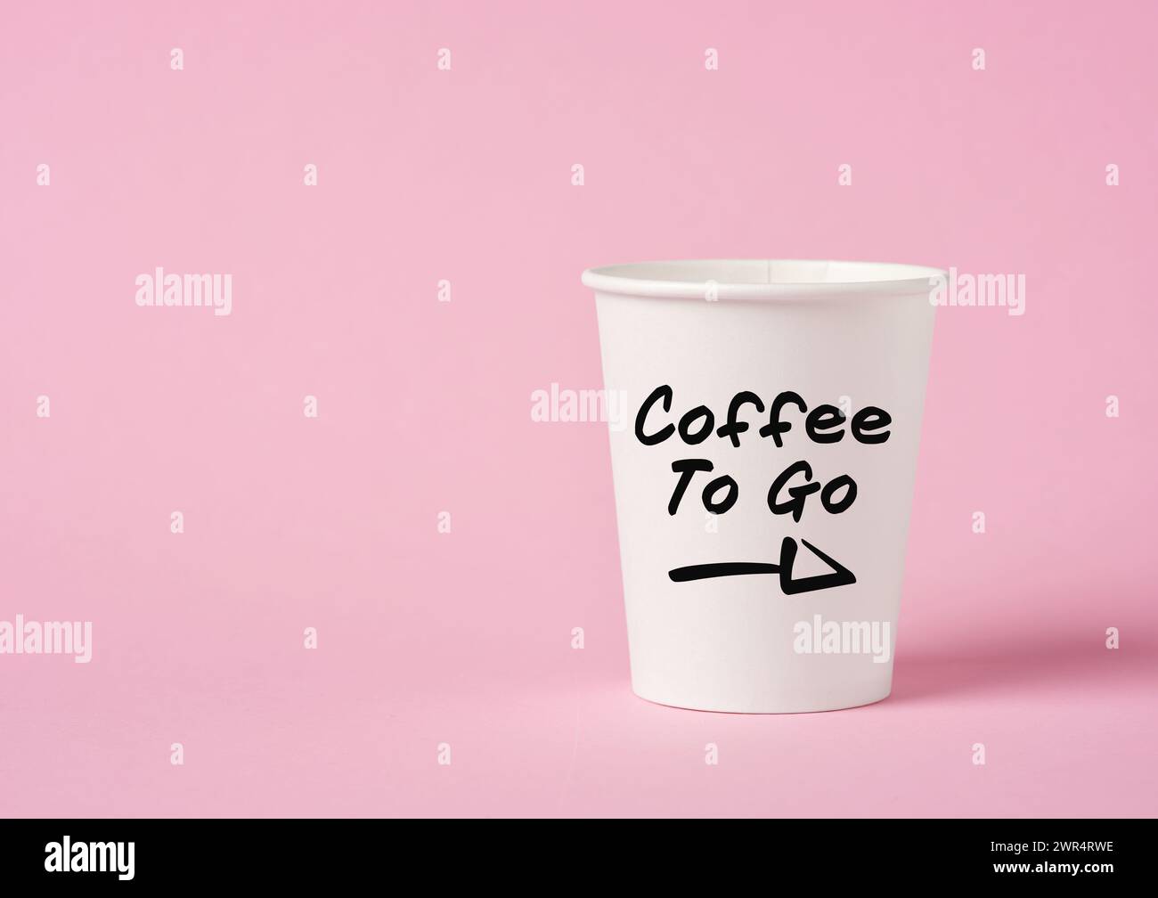 La parola caffè per andare su una tazza di caffè di carta su sfondo rosa. Foto Stock