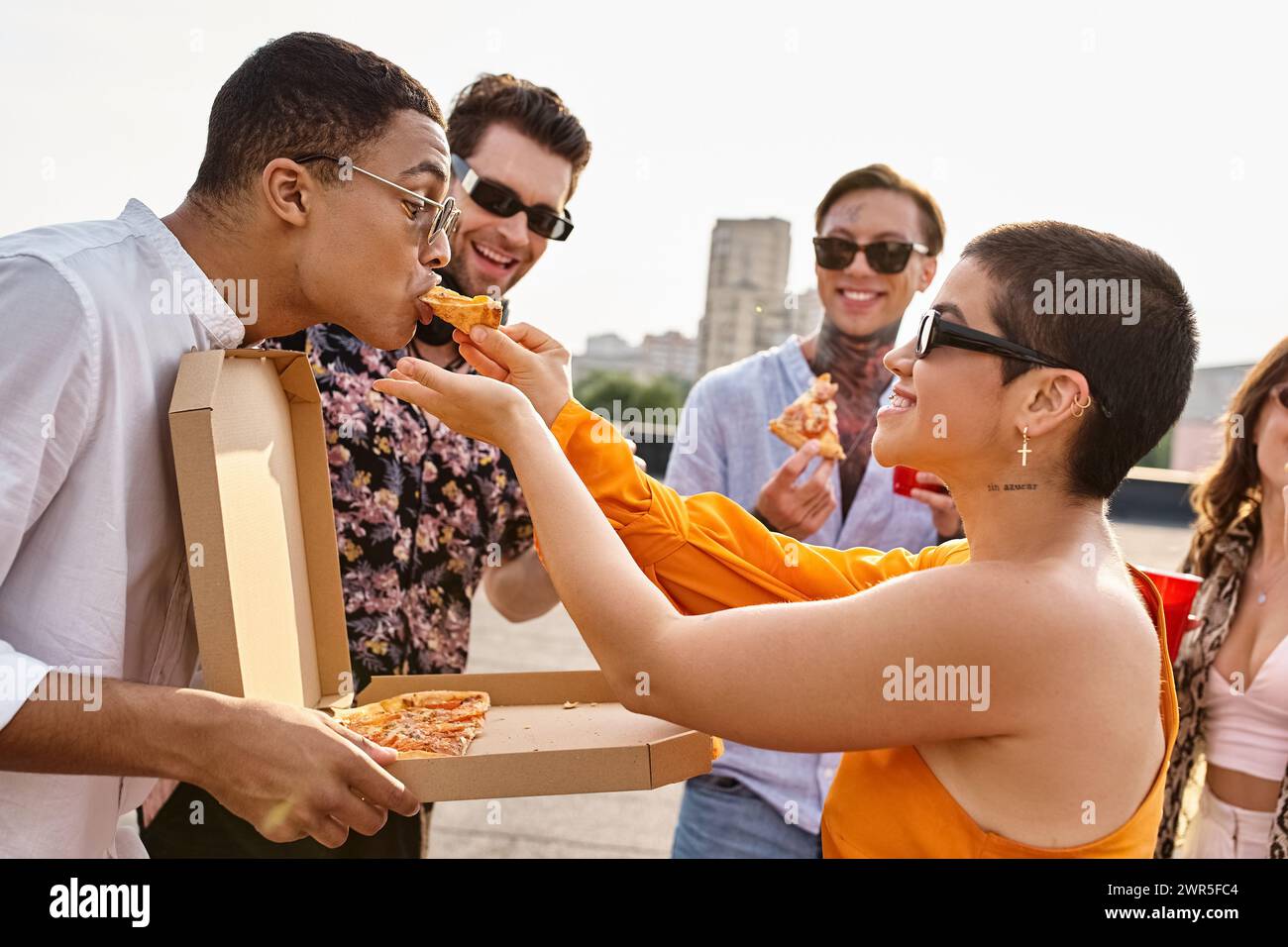 gente allegra e multirazziale con occhiali da sole alla moda che mangia pizza e beve cocktail alla festa Foto Stock