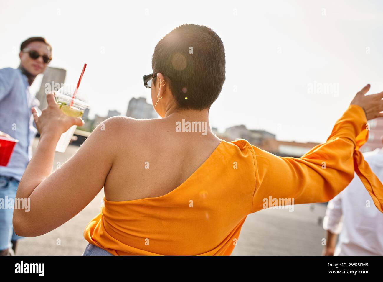 giovane donna alla moda con alcol bere in mano facendo festa sul tetto con il suo amico tatuato Foto Stock