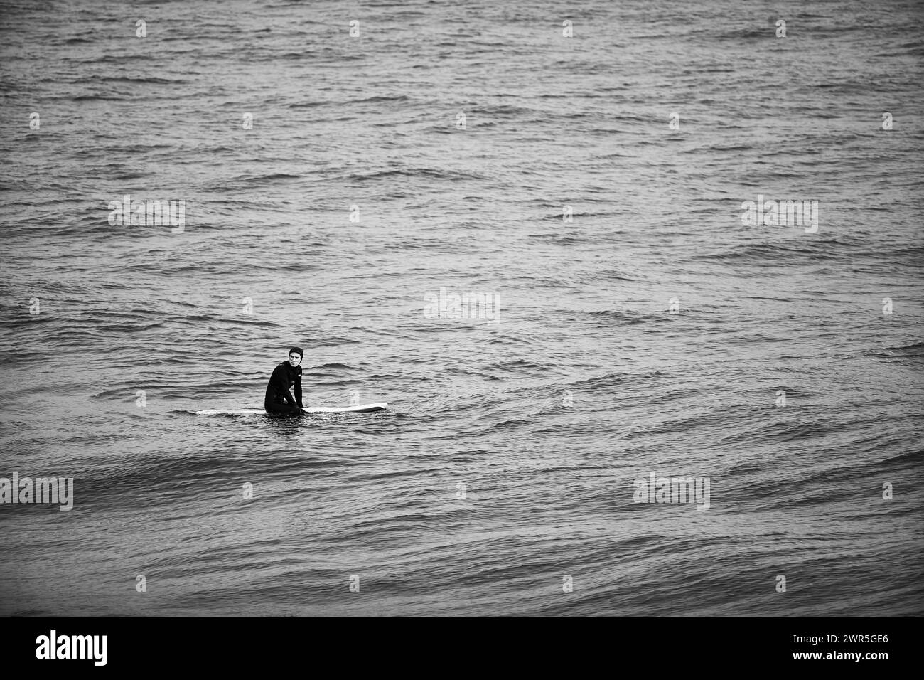 Un surfista in attesa delle onde sul mare Foto Stock