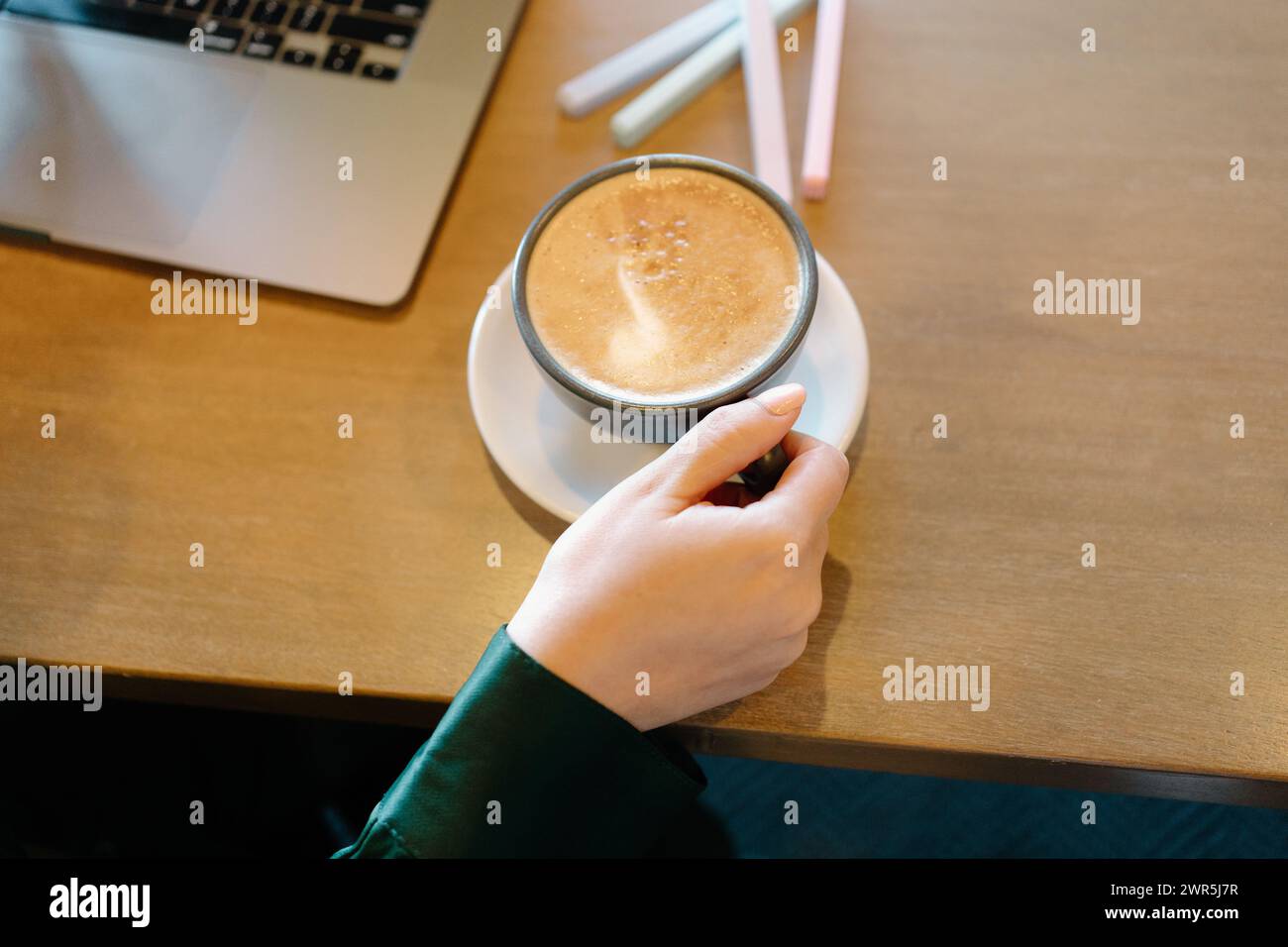 La donna lavora con un computer portatile al bar mentre beve un caffè Foto Stock