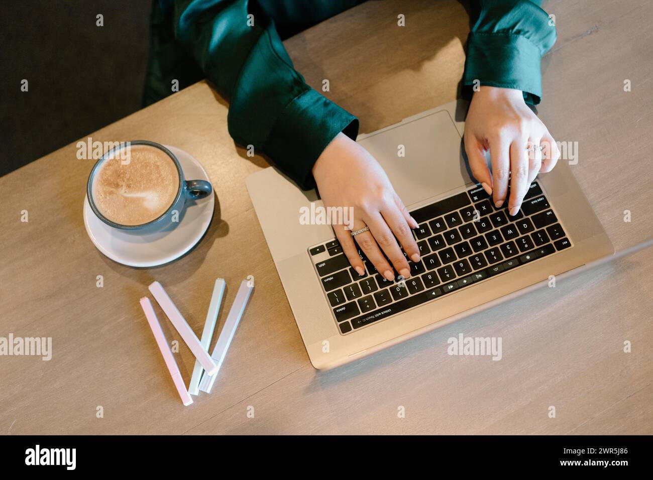La donna lavora con un computer portatile al bar mentre beve un caffè Foto Stock