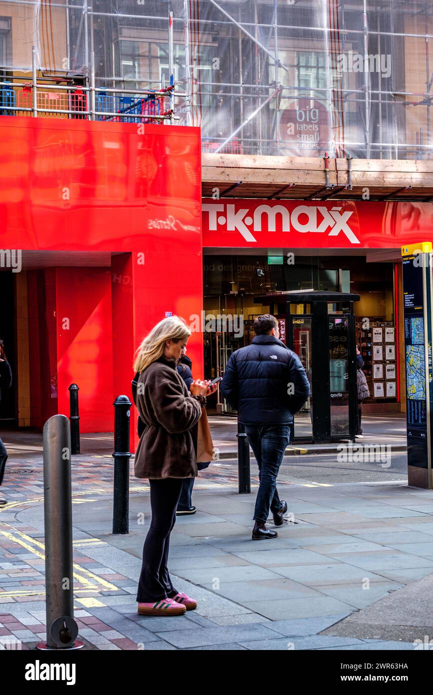 City of Westminster, Londra, Regno Unito, 8 marzo 2024, donna che usa il telefono cellulare in piedi fuori T K Maxx Shop Foto Stock