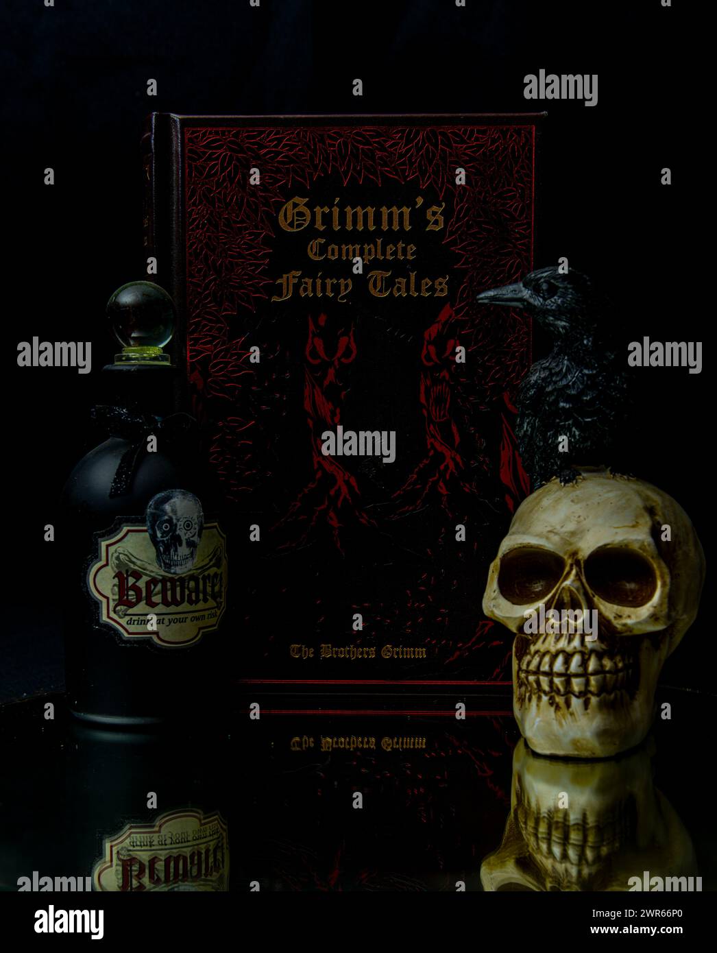 Un libro di fiabe Grimm accanto ad una bottiglia di alcol e ad un teschio spaventoso Foto Stock