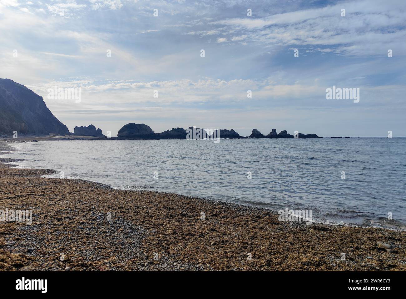 spiaggia tranquilla con formazioni rocciose, acque calme e un cielo nuvoloso che creano un'atmosfera tranquilla Foto Stock