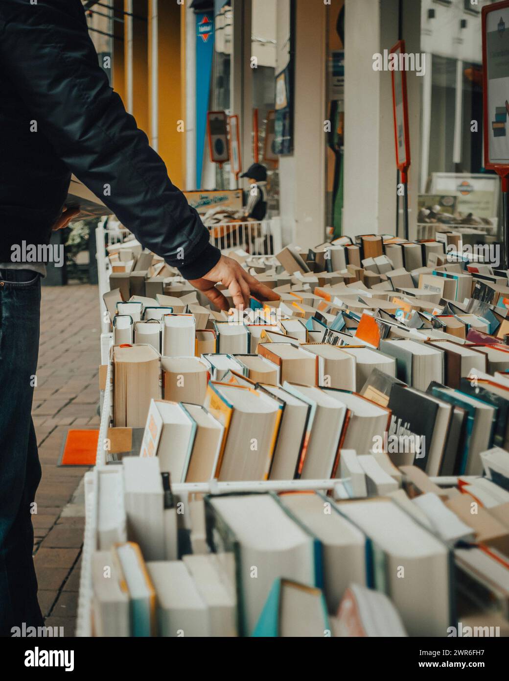 Un uomo che sfoglia libri al mercato all'aperto mentre passeggia Foto Stock