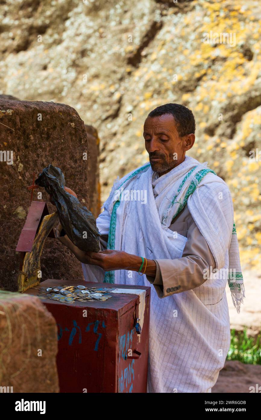 Lalibela, Etiopia - 1 maggio 2019: L'uomo conta i fondi raccolti dai fedeli fuori St. George Church, Lalibela, che fa luce sul servizio finanziario Foto Stock