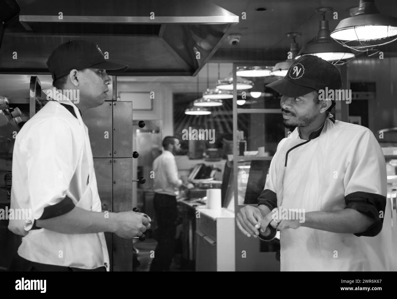 Nella vivace cucina del ristorante, due chef esperti elaborano meticolosamente piatti deliziosi con maestria e finezza Foto Stock