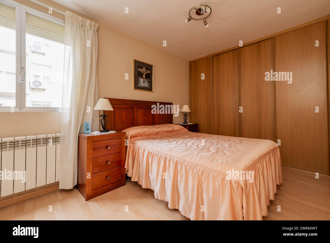 Una camera matrimoniale con mobili in legno, un grande armadio attaccato alla parete e una brutta trapunta sul letto Foto Stock