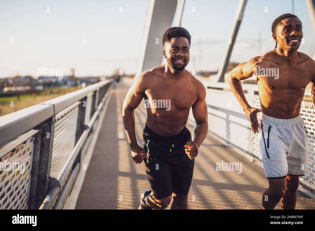 Due amici afroamericani fanno jogging sul ponte della città. Foto Stock