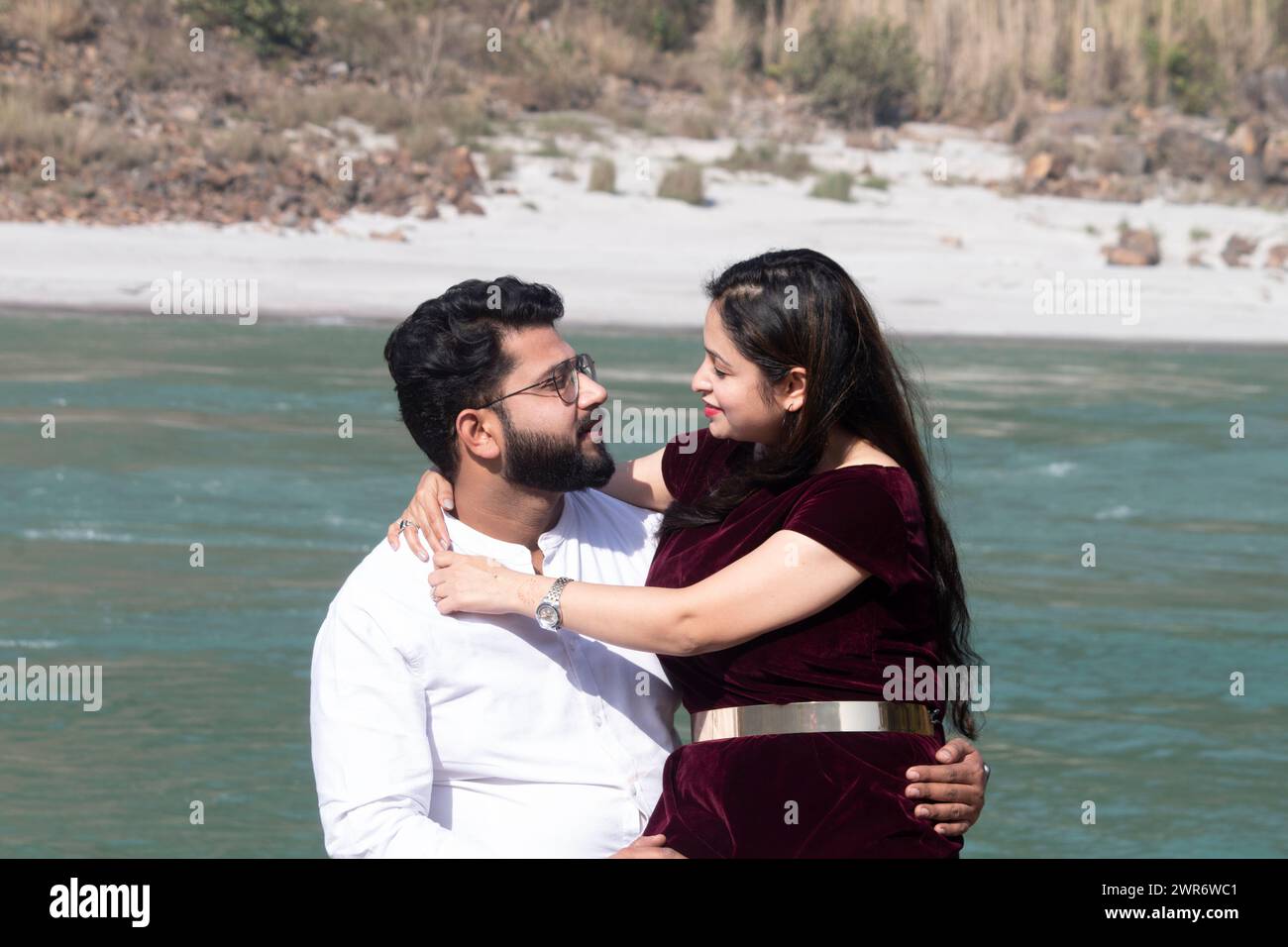 L'amore fiorisce dai Gange a Rishikesh mentre una coppia condivide un momento tenero seduta faccia a faccia, abbracciata dal flusso rilassante delle acque Foto Stock