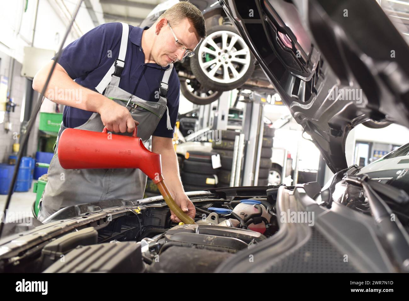 Cambio di olio motore dalla macchina da un meccanico in officina per auto Foto Stock Cambio di olio motore dalla macchina da un meccanico in officina per auto Foto Stock