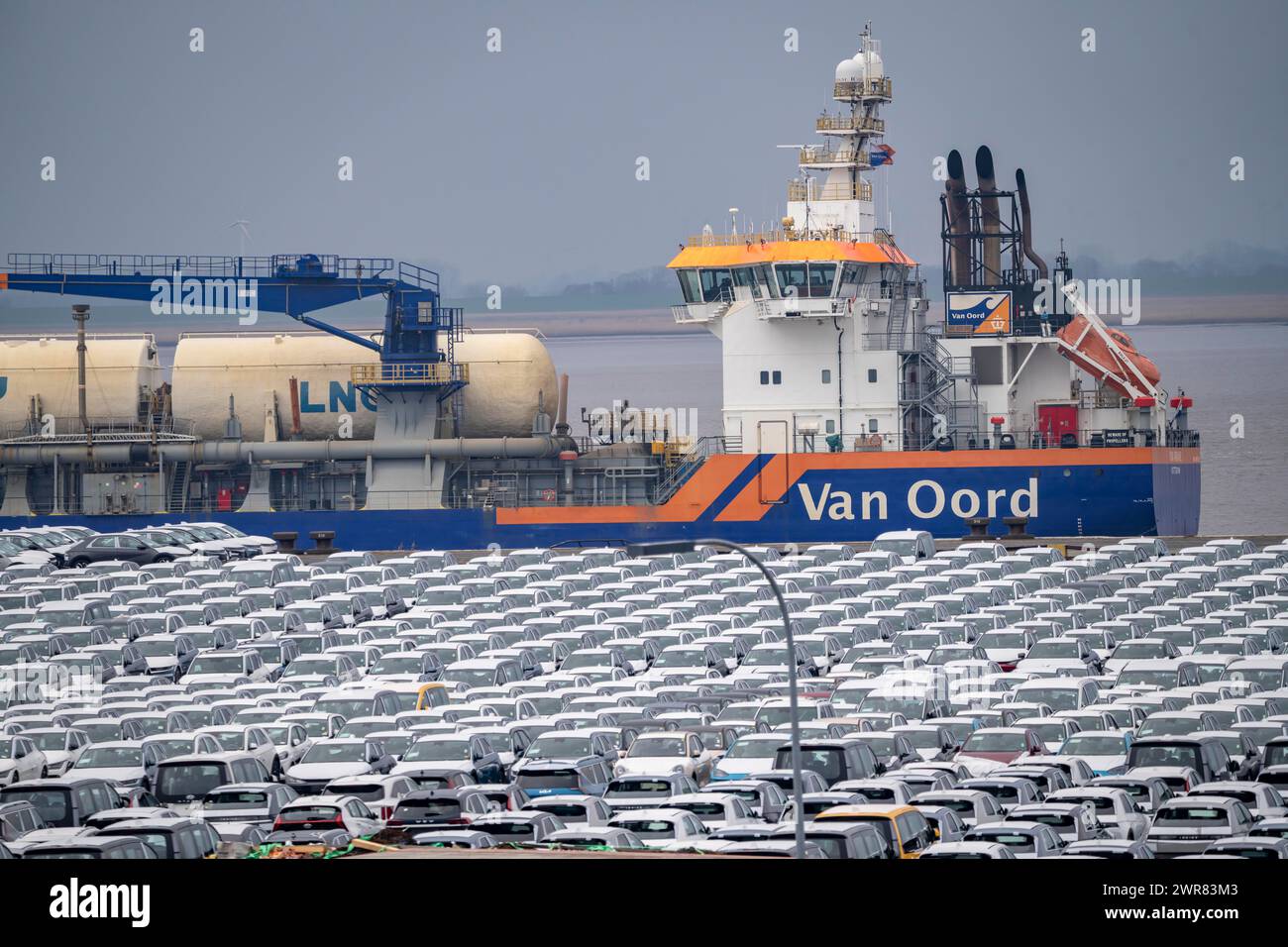 Parcheggio per veicoli d'importazione, centinaia di Hyundai Ioniq, auto elettriche, in attesa di un ulteriore trasporto, dietro di loro, sul Weser, la draga Foto Stock