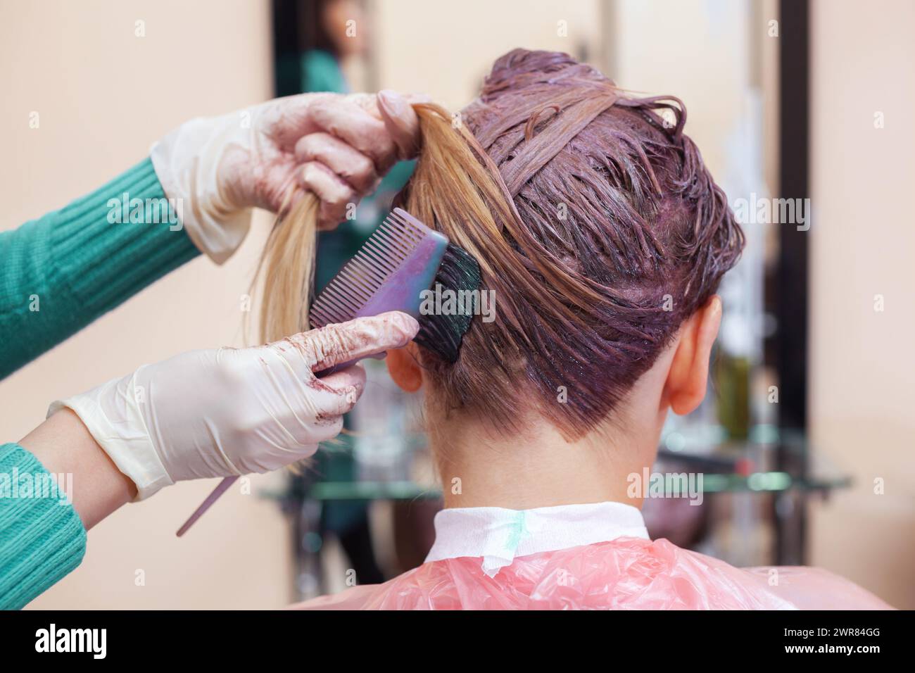 Il parrucchiere dipinge i capelli della donna in bianco, applica la vernice ai capelli nel salone di bellezza. Foto Stock