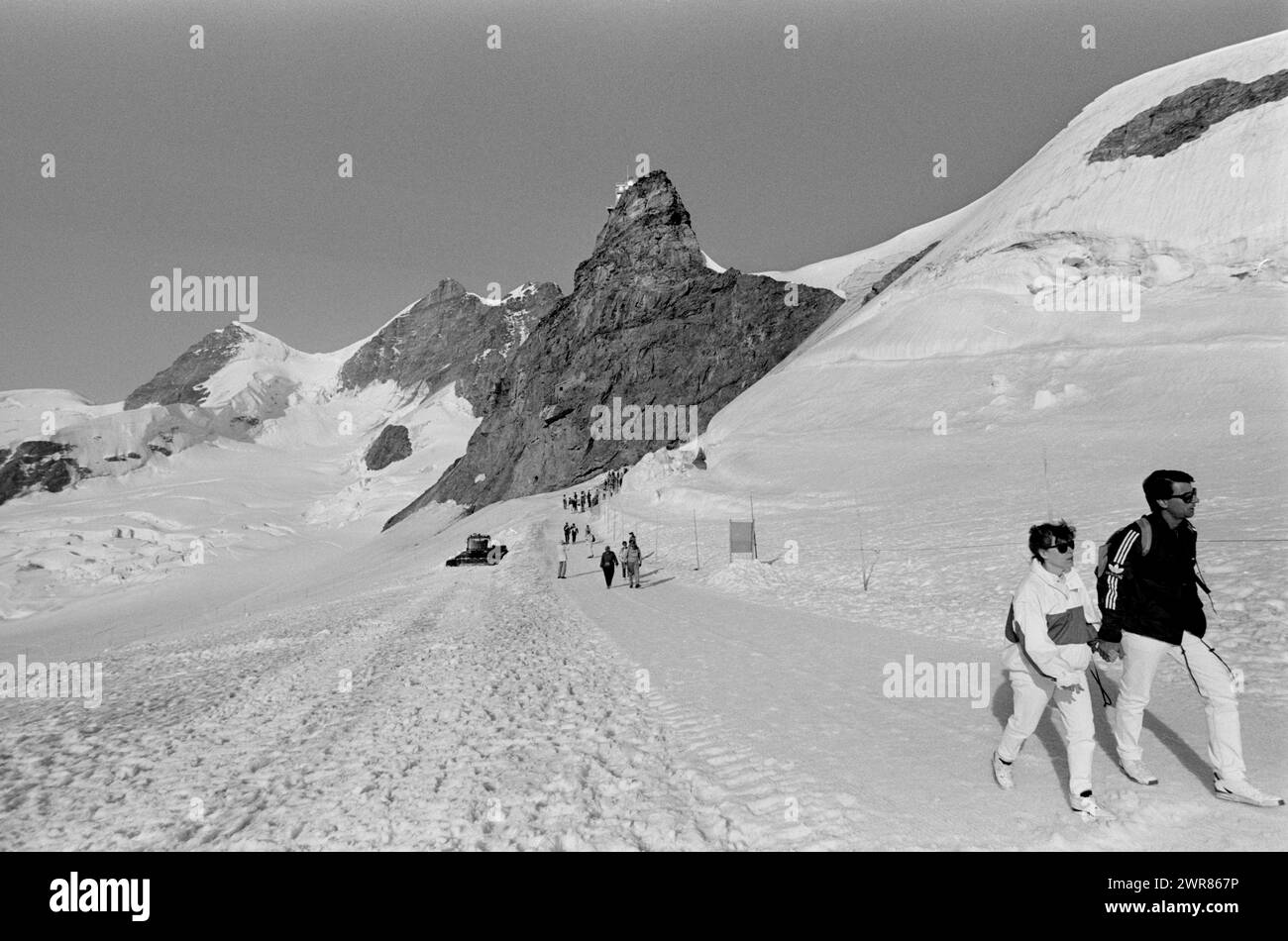 La vetta svizzera dello Jungfraujoch mostra gli escursionisti che si godono il ghiacciaio Aletsch nei mesi estivi 1991 turisti che camminano fino al rifugio Monchsjoch sopra il ghiacciaio Aletsch. Nella zona conosciuta come il Top of Europe. Questa scansione è stata eseguita nel 2024 Foto Stock