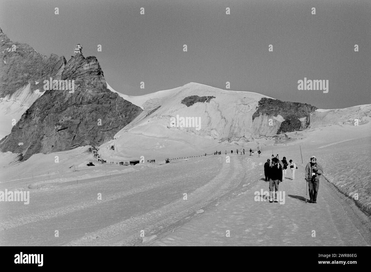 La vetta svizzera dello Jungfraujoch mostra gli escursionisti che si godono il ghiacciaio Aletsch nei mesi estivi 1991 turisti che camminano fino al rifugio Monchsjoch sopra il ghiacciaio Aletsch. Nella zona conosciuta come il Top of Europe. Questa scansione è stata eseguita nel 2024 Foto Stock