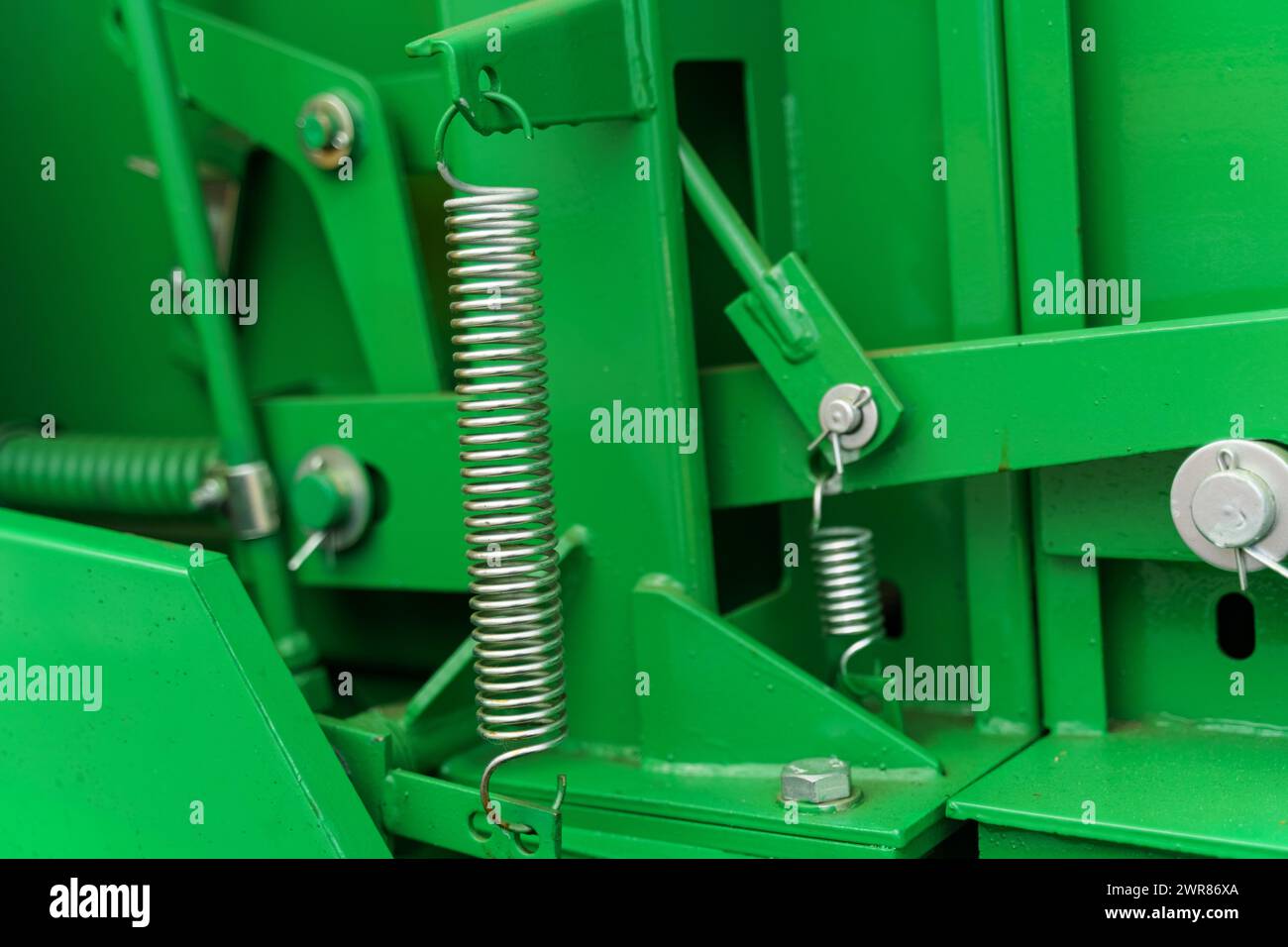 Uno sguardo dettagliato alle parti meccaniche delle apparecchiature industriali verdi, mostrando molle e collegamenti imbullonati come parte del complessivo macchinario. Foto Stock