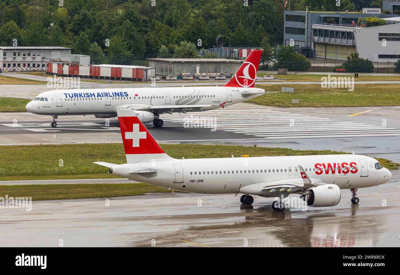 Ein Airbus A321-200 von Turkish Airlines startet von piste 28 auf dem Flughafen Zürich. Registrazione TC-JSC. Davor wartet ein Airbus A220-100 von SWIs Foto Stock