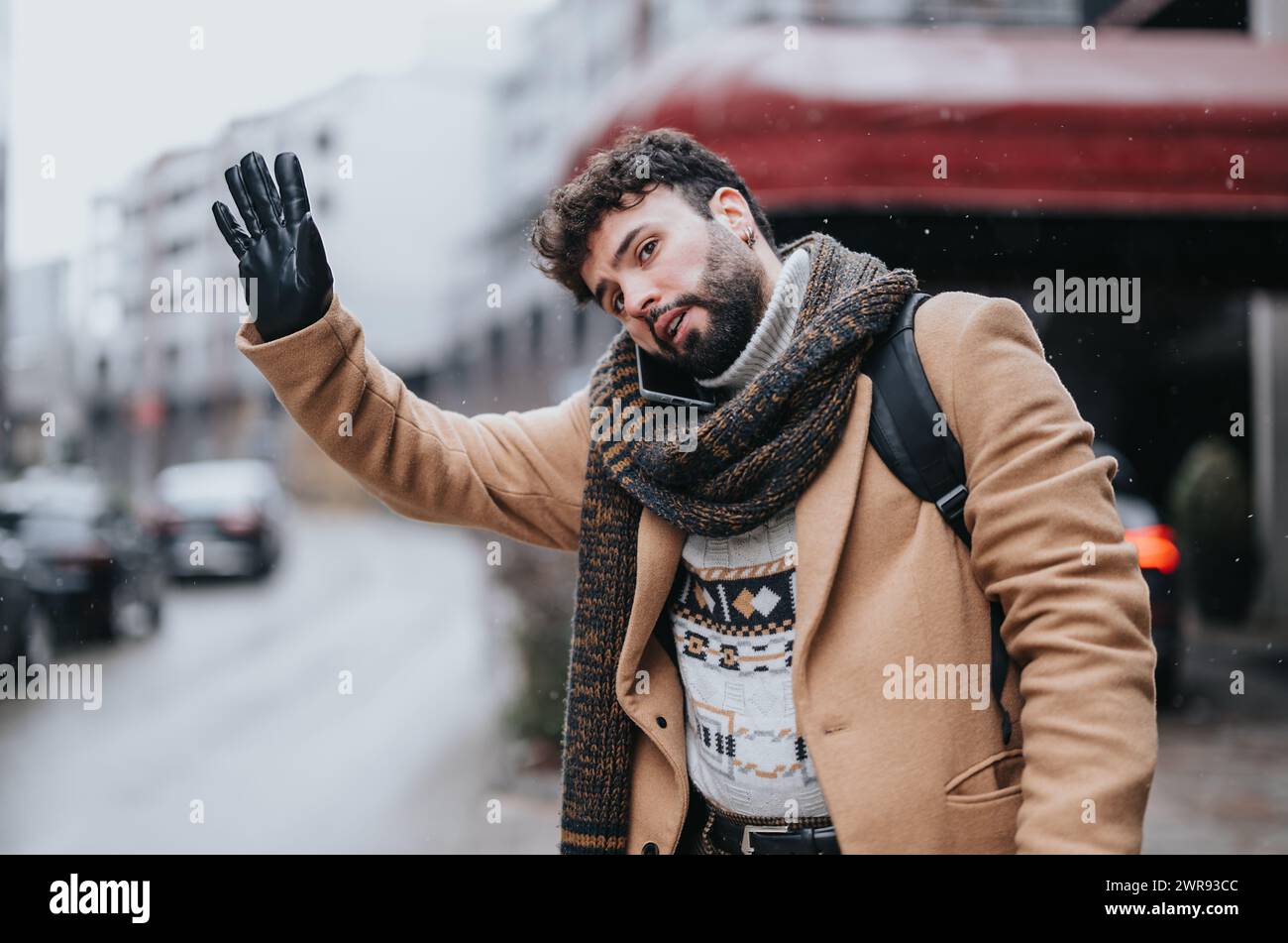 Giovane uomo d'affari sicuro che salta un taxi in una città innevata. Foto Stock