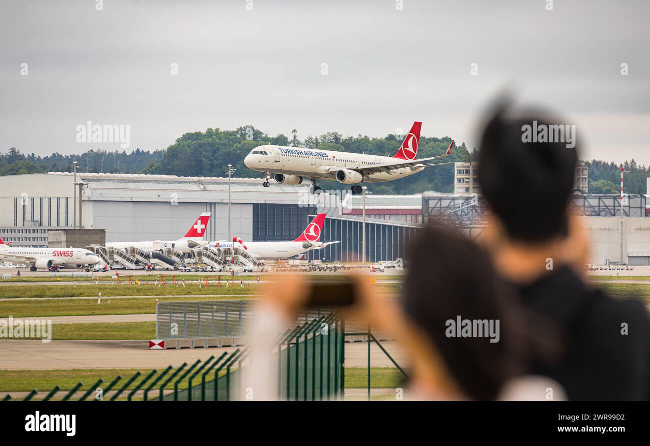 Einige Zuschauer beobachten vom Zuschauerhügel am Flughafen Zürich wie ein Airbus A321-231 von THY Turkish Airlines auf dem Flughafen Zürich landet. R Foto Stock